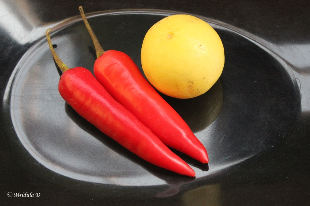 Red Chillis and a Lemon on Black Background