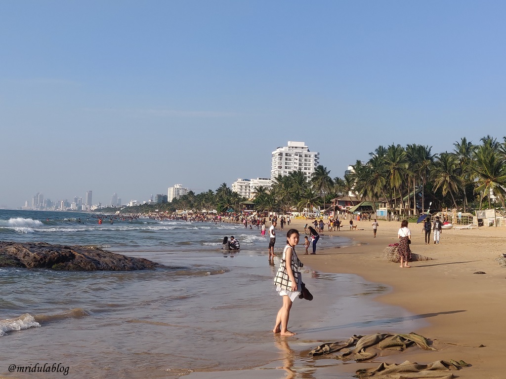 Tourists at Mt. Lavinia beach in Sri lanka with Colombo Skyline visible in far distance 